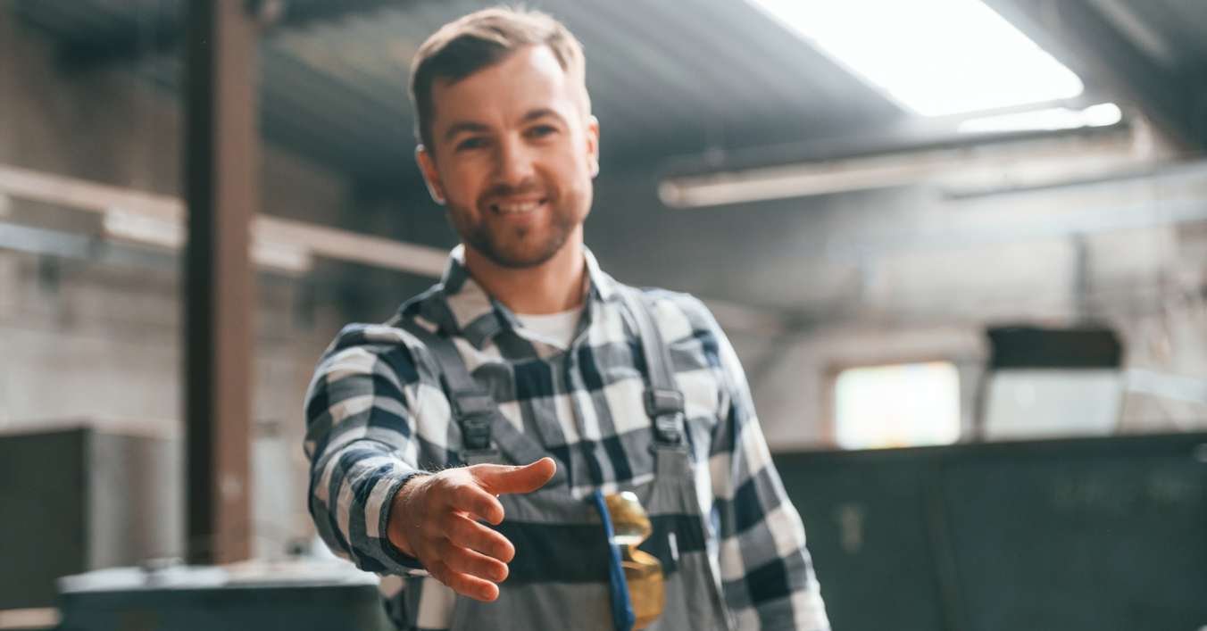 Tradesman extending a hand in a workshop